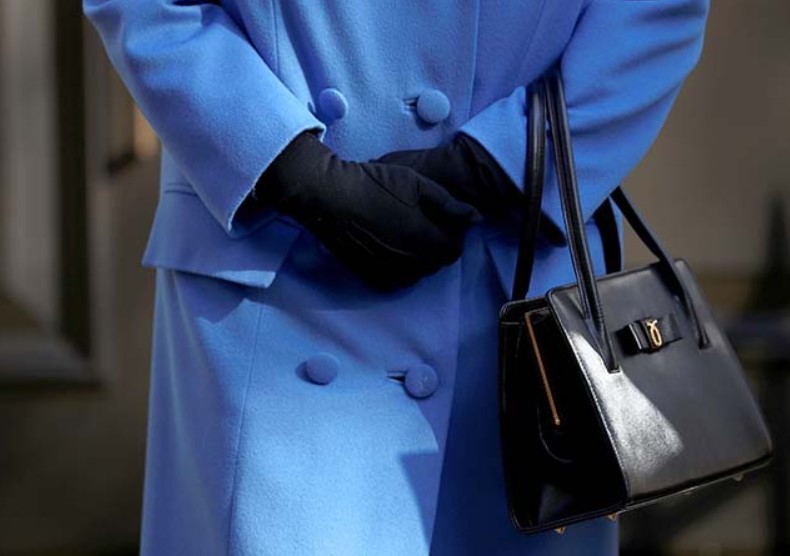 Faceless woman holding black purse with black gloves